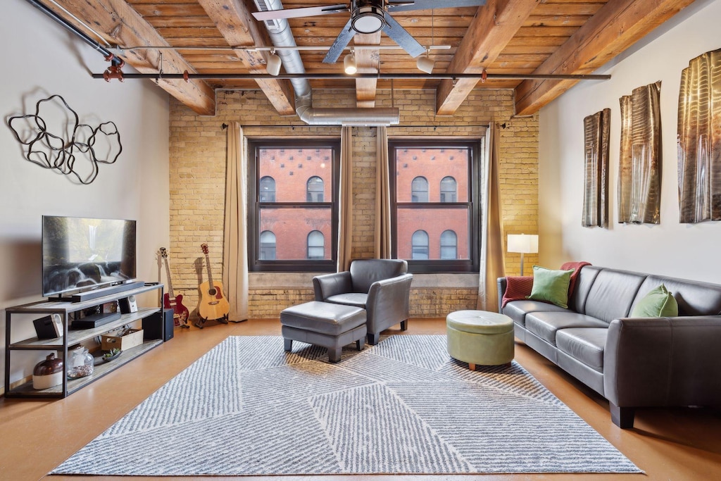 sitting room with wood ceiling, ceiling fan, brick wall, and beam ceiling