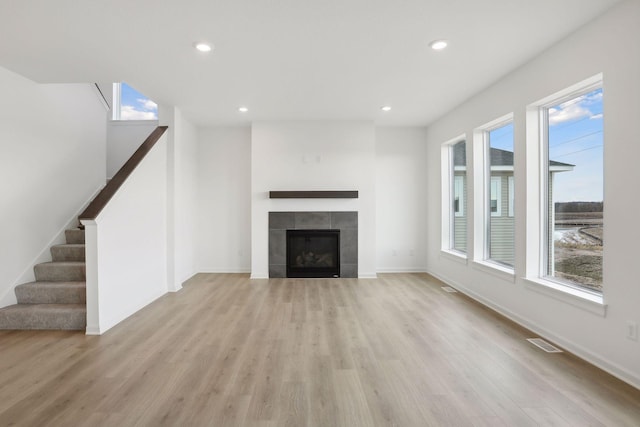 unfurnished living room featuring a tiled fireplace and light hardwood / wood-style flooring