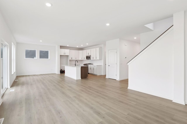 unfurnished living room with sink and light wood-type flooring