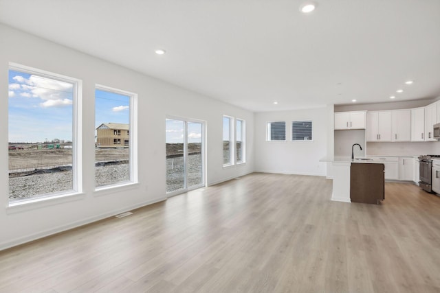 unfurnished living room featuring sink and light wood-type flooring