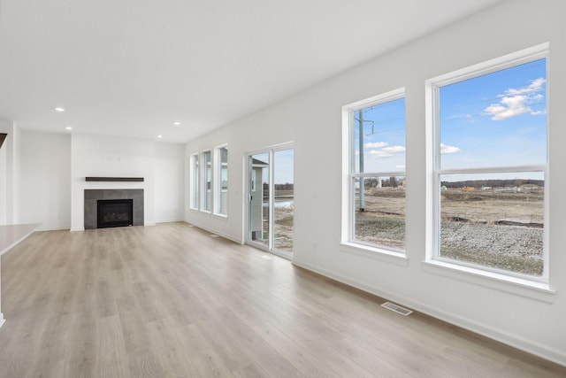 unfurnished living room with a tiled fireplace and light hardwood / wood-style flooring