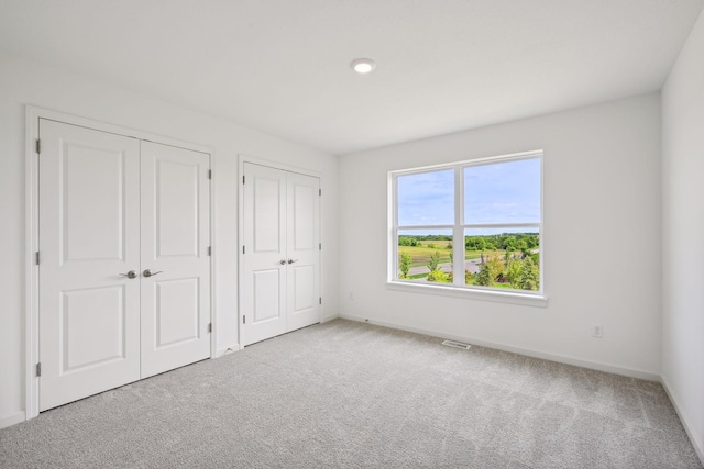 unfurnished bedroom with carpet floors and two closets