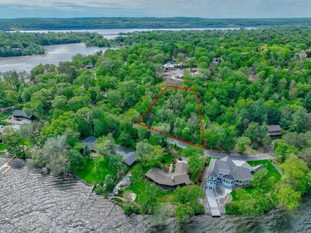 aerial view of property and surrounding area with a forest, a nearby body of water, and property boundaries highlighted