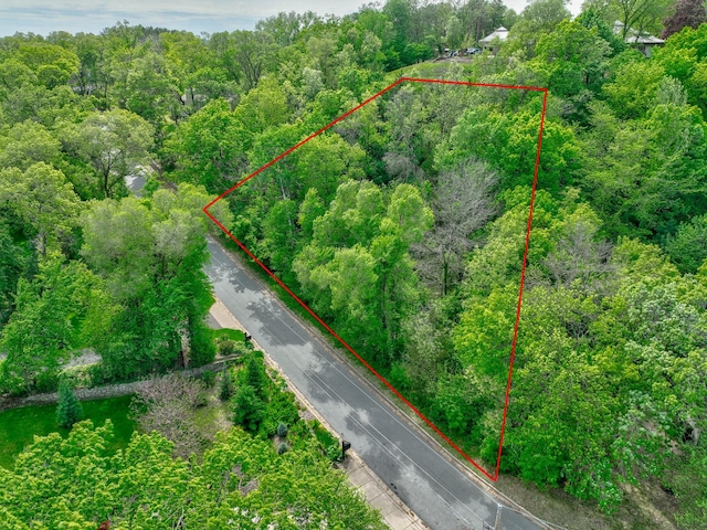 aerial view of property and surrounding area with property parcel outlined and a heavily wooded area