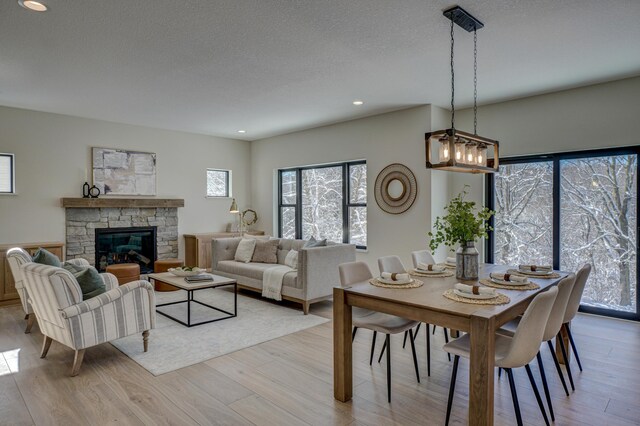 1205 Riverside Dr N, North Hudson, WI 54016 - dining space with light wood finished floors, recessed lighting, a stone fireplace, and a textured ceiling