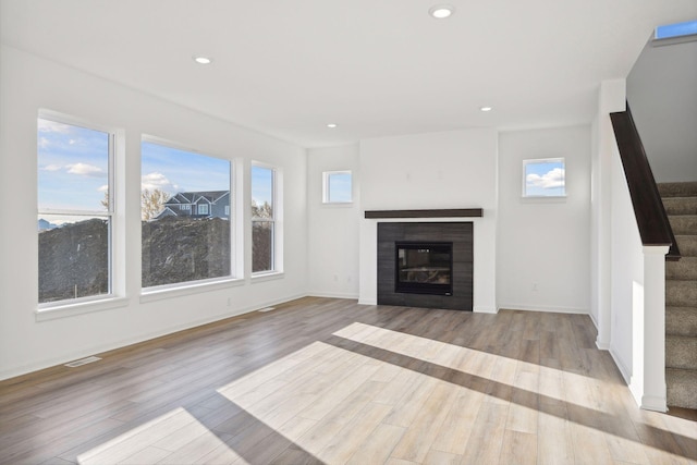 unfurnished living room featuring plenty of natural light and light hardwood / wood-style floors