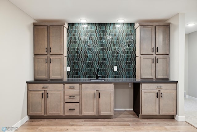 bar featuring tasteful backsplash, sink, and light hardwood / wood-style flooring