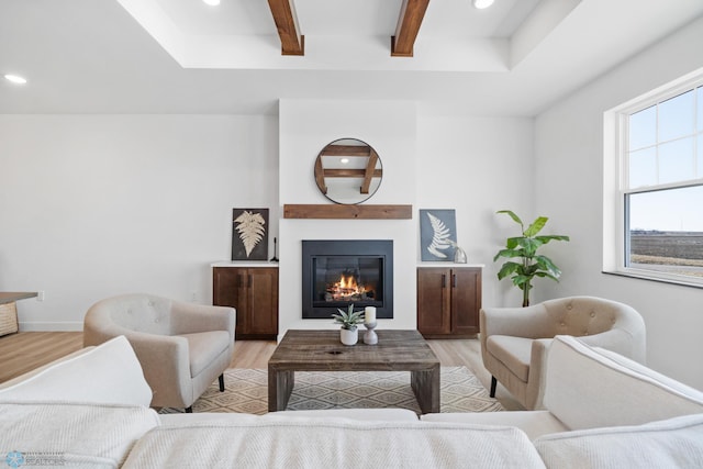 living room featuring light wood-style floors, a glass covered fireplace, beam ceiling, and recessed lighting