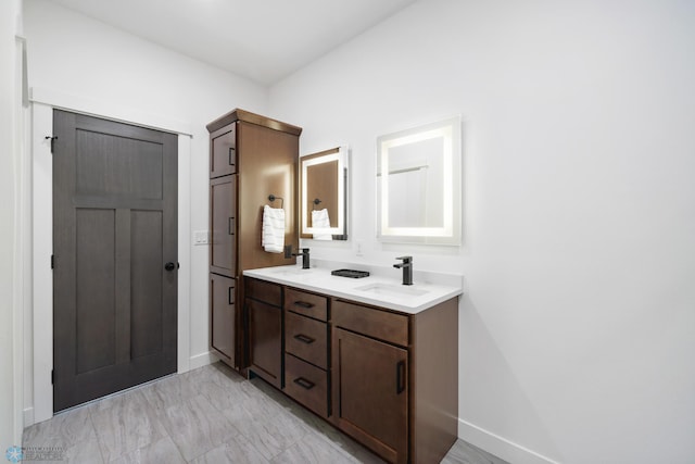 bathroom featuring baseboards, double vanity, marble finish floor, and a sink