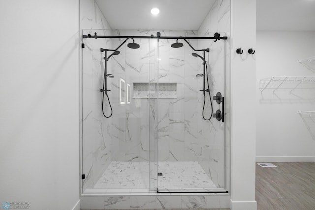 bathroom with a walk in closet, baseboards, and a marble finish shower