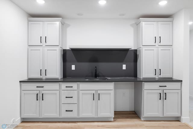 bar with a sink, light wood-style flooring, recessed lighting, and baseboards