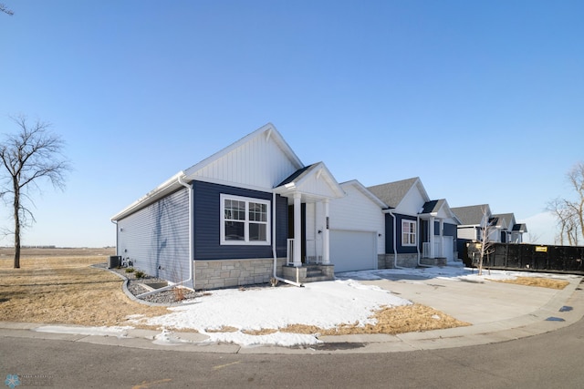 view of front of home with driveway, cooling unit, board and batten siding, stone siding, and a garage