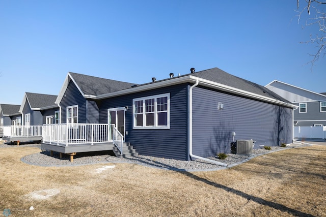 view of property exterior featuring central AC, a deck, a yard, and roof with shingles
