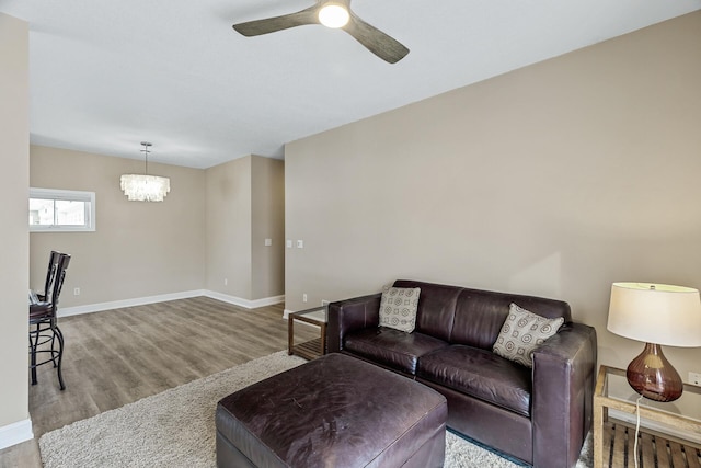 living room with ceiling fan with notable chandelier and light hardwood / wood-style floors