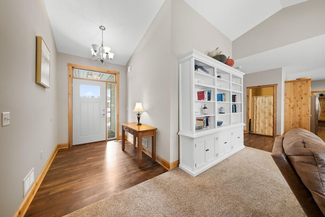 foyer entrance featuring an inviting chandelier, lofted ceiling, and dark hardwood / wood-style flooring