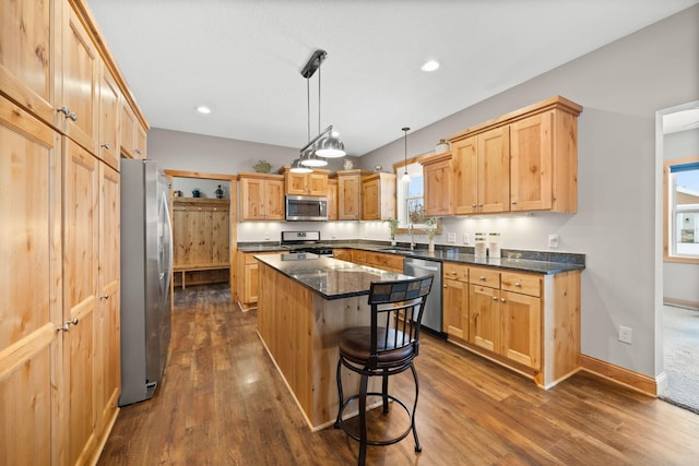 kitchen with pendant lighting, sink, appliances with stainless steel finishes, a center island, and a kitchen bar