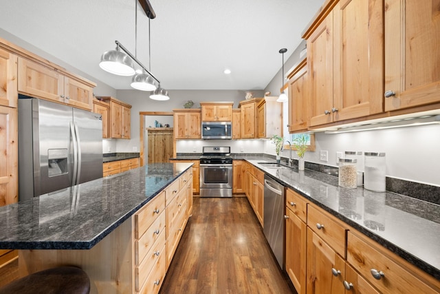 kitchen featuring stainless steel appliances, hanging light fixtures, a kitchen island, and dark stone countertops