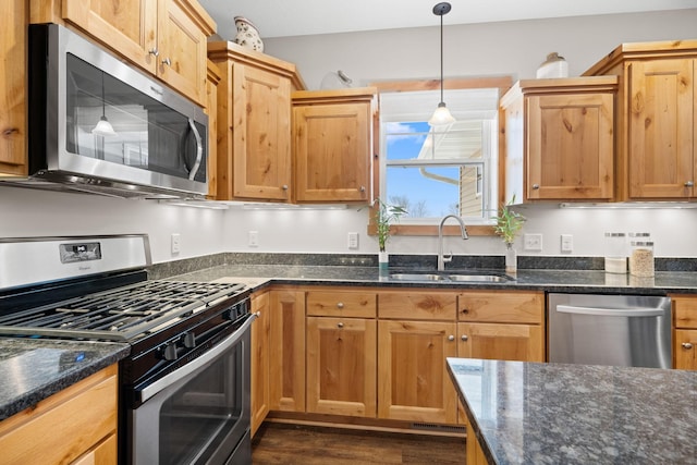 kitchen with dark stone countertops, sink, decorative light fixtures, and stainless steel appliances