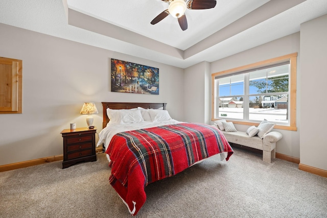 bedroom featuring a raised ceiling, ceiling fan, and carpet