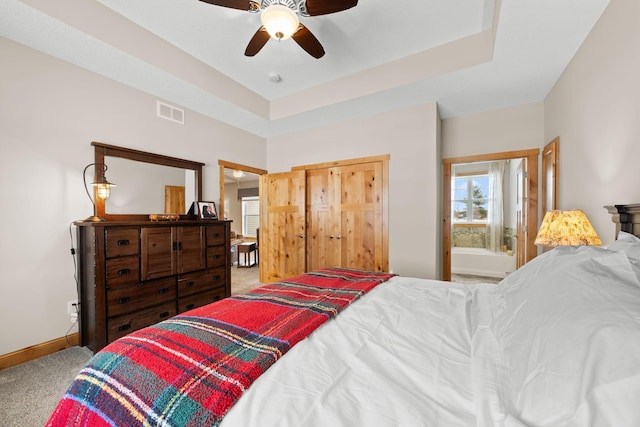 carpeted bedroom with ceiling fan and a raised ceiling