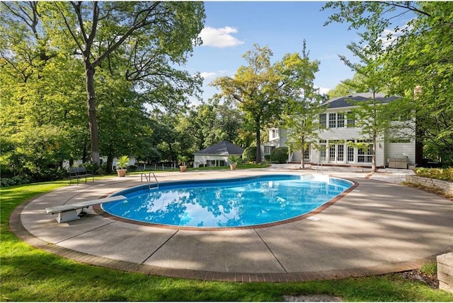 view of swimming pool featuring a patio, a diving board, an outbuilding, and french doors