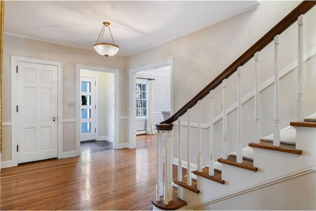 foyer entrance with ornamental molding, wood-type flooring, and a baseboard heating unit