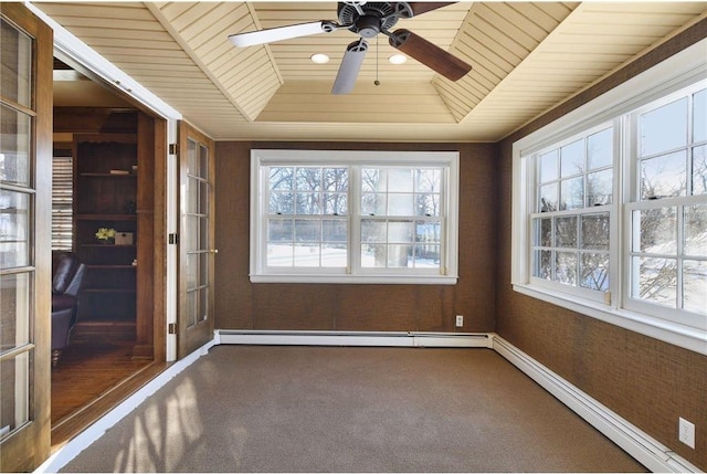 unfurnished sunroom featuring wood ceiling, a tray ceiling, a wealth of natural light, and baseboard heating