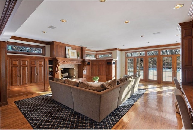 living room featuring hardwood / wood-style flooring, ornamental molding, and a high end fireplace