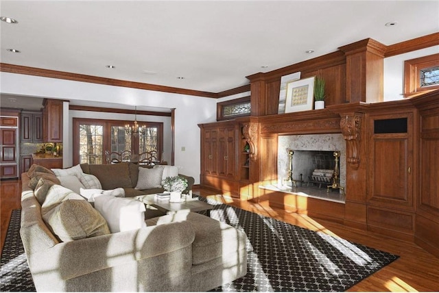 living room featuring a premium fireplace, crown molding, hardwood / wood-style floors, and a chandelier