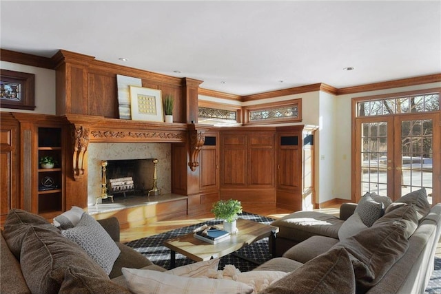 living room with crown molding, light hardwood / wood-style flooring, a high end fireplace, and french doors