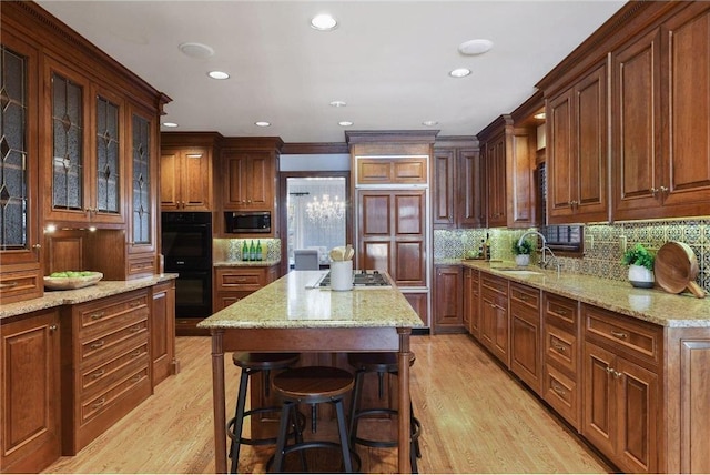 kitchen featuring sink, a breakfast bar area, a kitchen island, stainless steel appliances, and light stone countertops