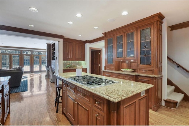 kitchen featuring ornamental molding, stainless steel gas stovetop, a kitchen bar, and a center island