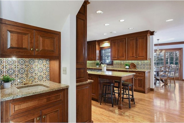 kitchen with light stone counters, a center island, a breakfast bar, and light hardwood / wood-style floors