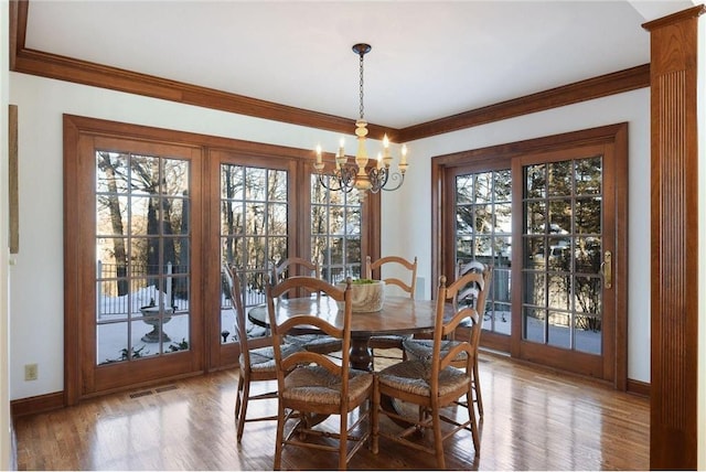 dining area featuring a notable chandelier, wood-type flooring, and ornamental molding