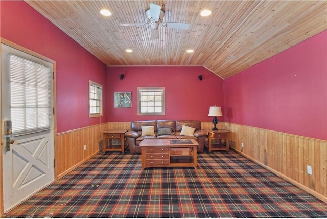 living area with dark colored carpet, wood ceiling, and wood walls