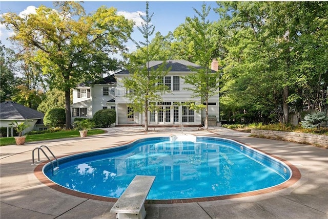 view of swimming pool with a patio area, a diving board, and french doors