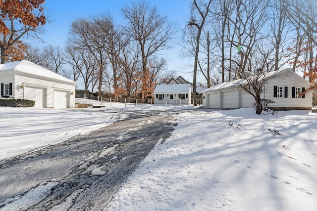 yard layered in snow featuring a garage and an outdoor structure