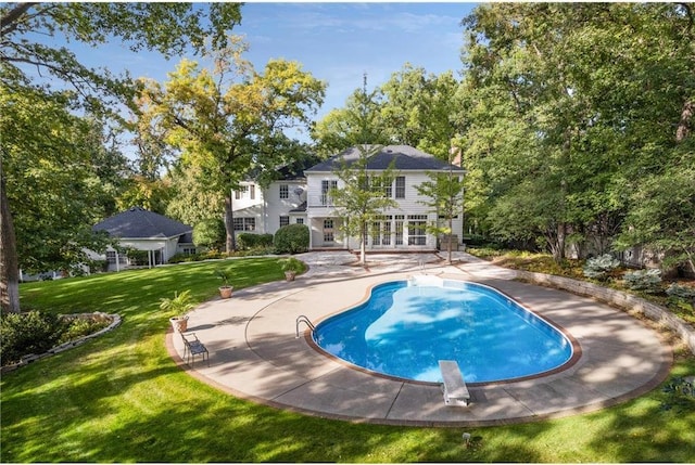 pool featuring a lawn, a diving board, a patio area, and french doors
