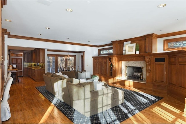 living room with a high end fireplace, ornamental molding, wood finished floors, and a healthy amount of sunlight