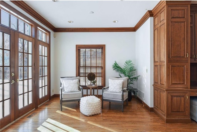 living area with french doors, ornamental molding, baseboards, and light wood-type flooring