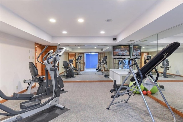 exercise area featuring recessed lighting, baseboards, and a raised ceiling