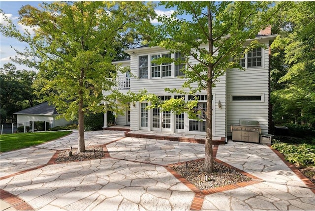 back of house with french doors, a chimney, a patio area, and a balcony