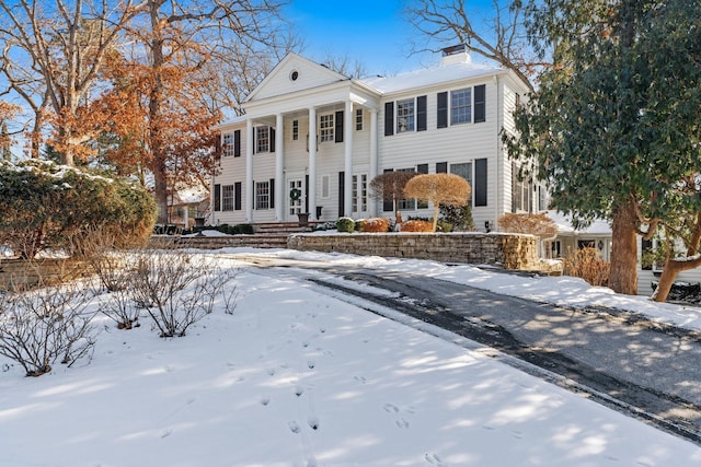 neoclassical / greek revival house featuring a porch and a chimney