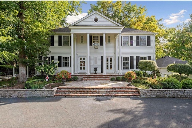 greek revival inspired property with fence and covered porch