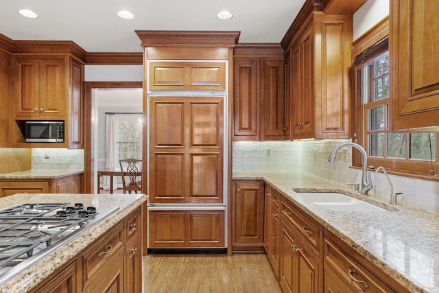 kitchen with built in appliances, backsplash, a healthy amount of sunlight, and a sink