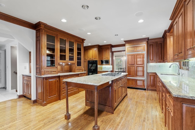 kitchen with built in appliances, recessed lighting, light wood-type flooring, brown cabinets, and a sink