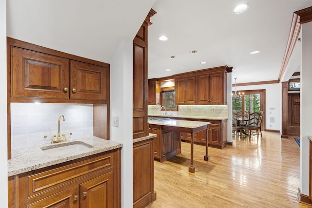 6321 Interlachen Blvd, Edina, MN 55436 - kitchen with a sink, brown cabinetry, light wood-type flooring, backsplash, and light stone countertops