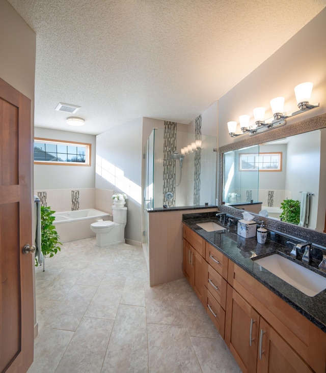 bathroom with a textured ceiling, tile patterned floors, a tub to relax in, and a sink