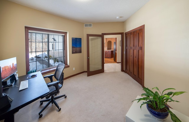 office featuring visible vents, light carpet, baseboards, and french doors