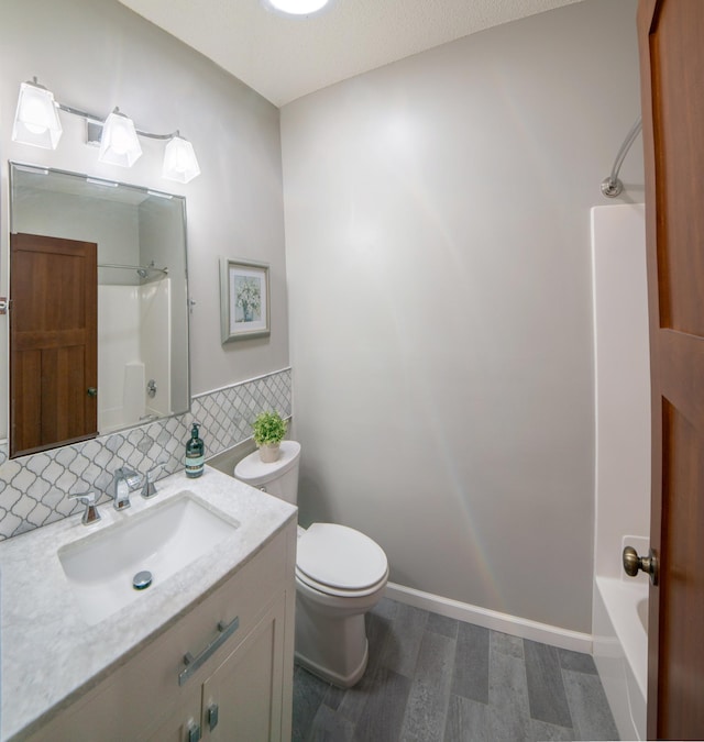 full bathroom with vanity, wood finished floors, baseboards, toilet, and backsplash